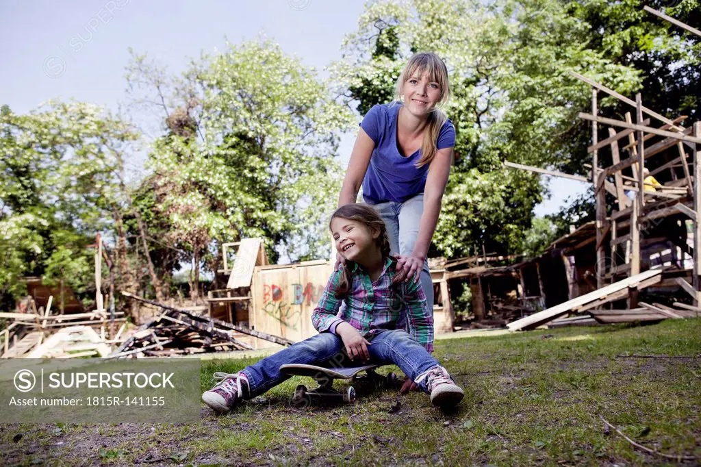 Germany, North Rhine Westphalia, Cologne, Mother and daughter playing with skateboard, smiling