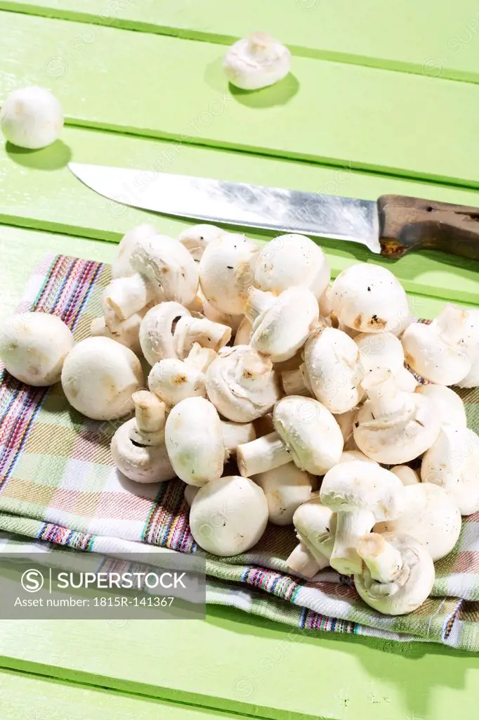 Mushrooms with kitchen knife on wooden table, close up