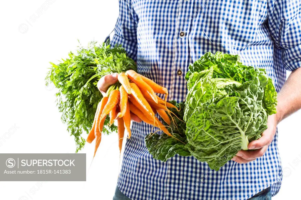 Mature man holding bunch of carrots and savoy cabbage, close up