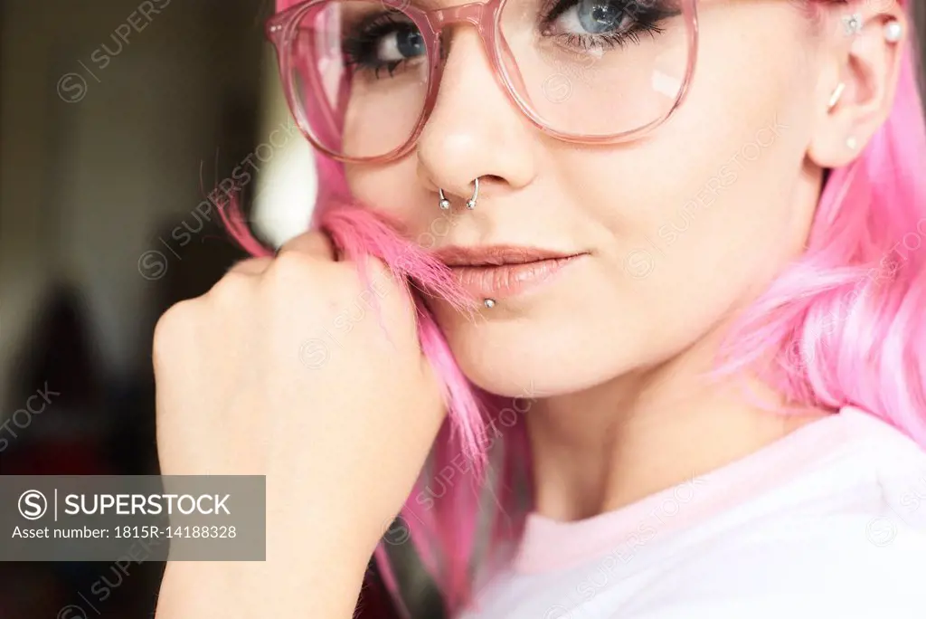 Portrait of young woman with pink hair, glasses and piercings