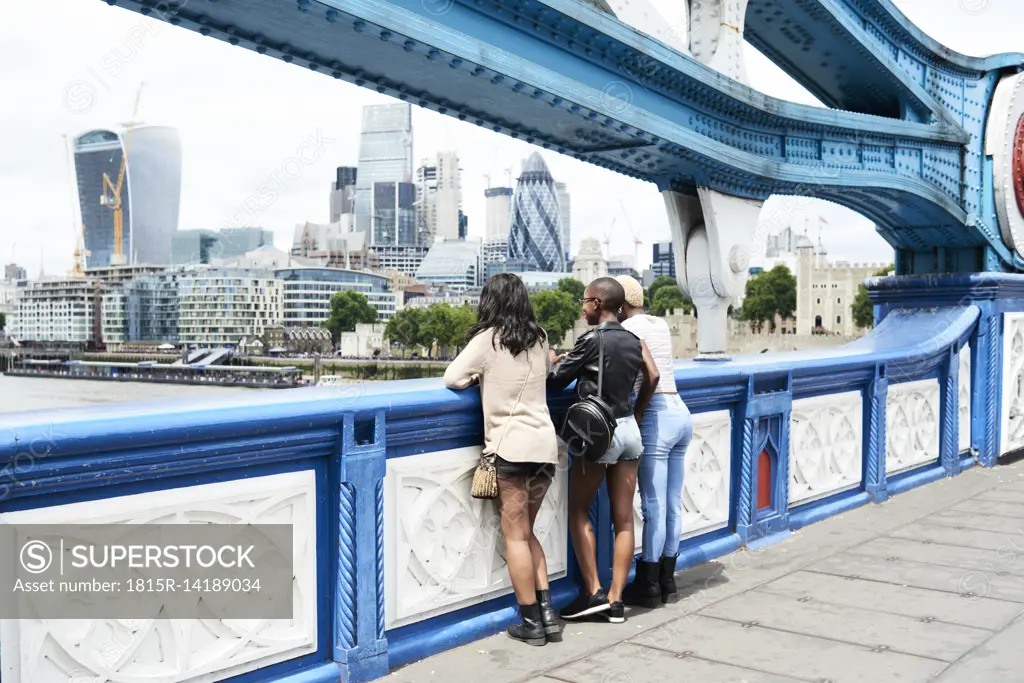 UK, London, back view of three friends looking at skyline