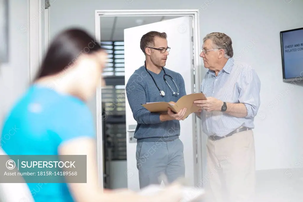 Doctor with file talking to patient in medical practice