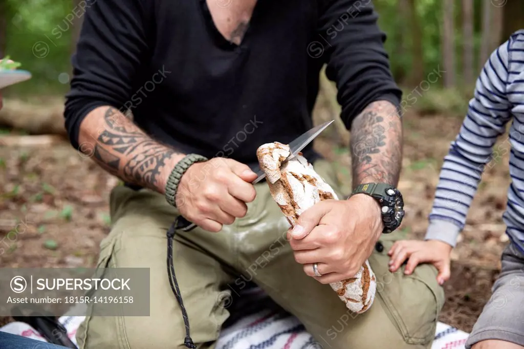 Man cutting bread during a picnic in forest