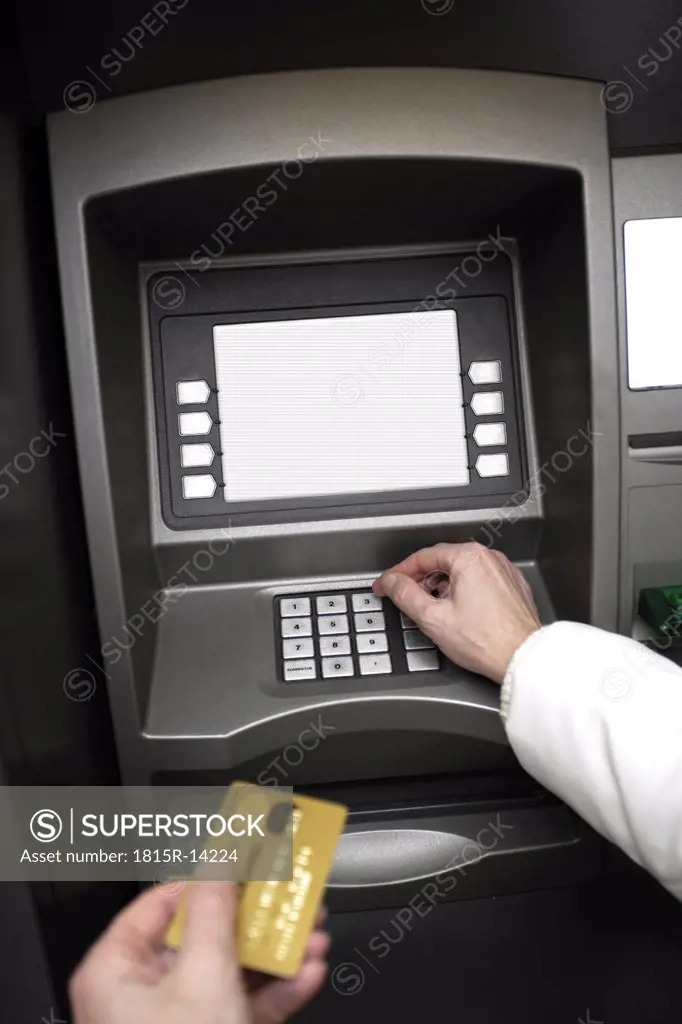 Person holding credit card, using ATM machine