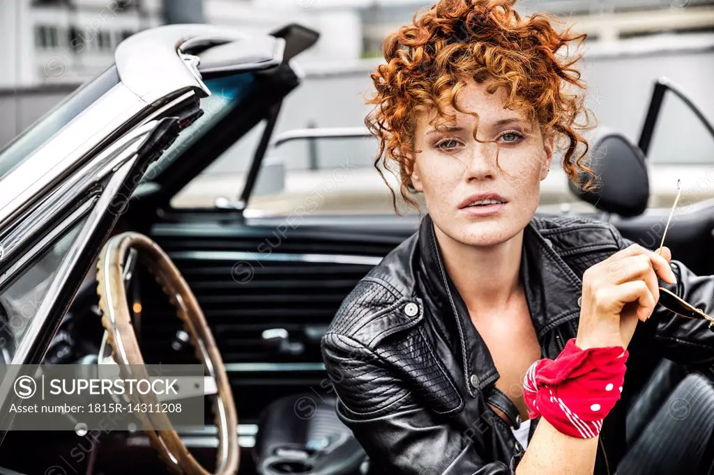 Portrait of confident redheaded woman in sports car