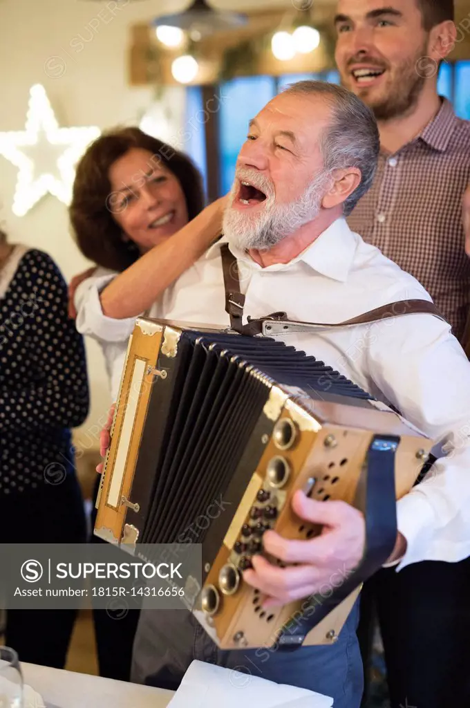 Senior man playing accordion for happy family at Christmas