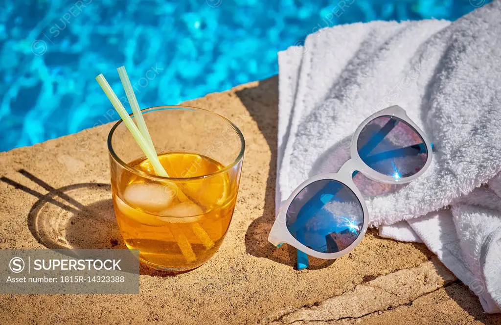 Glass of Crodino, sunglasses and towel at the poolside