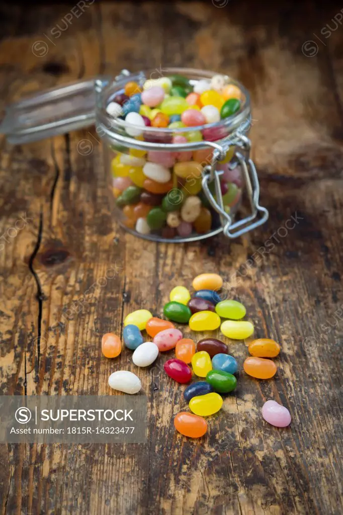 Glass of colourful sweet jellybeans on dark wood