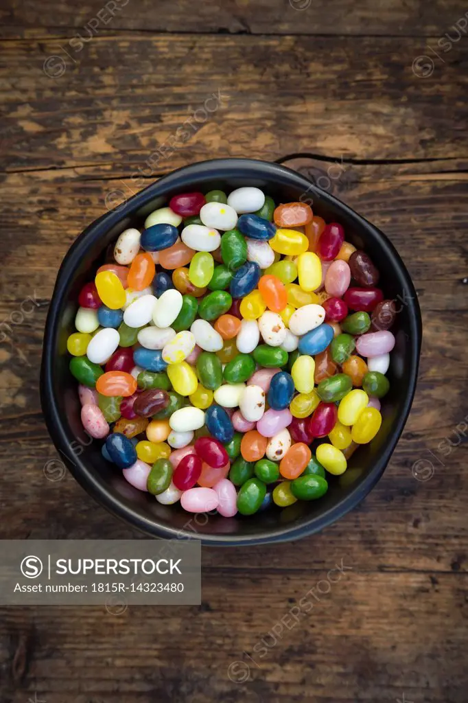 Bowl of colourful sweet jellybeans on dark wood