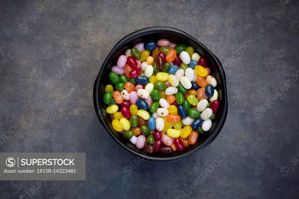 Bowl of colourful sweet jellybeans on grey background