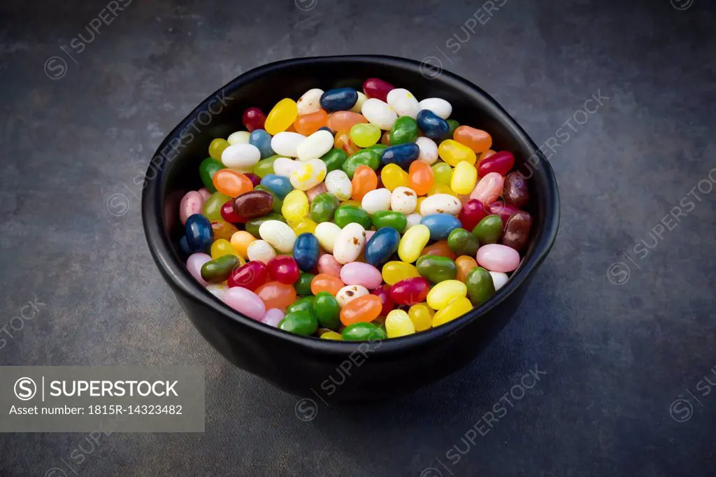 Bowl of colourful sweet jellybeans on grey background