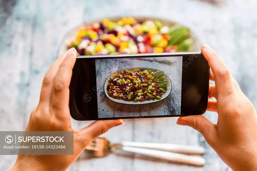 Girl taking picture of Quinoa salad with smartphone, close-up