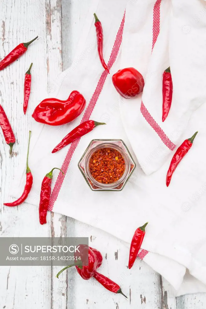 Glass of chili flakes and red chili pods on kitchen towel