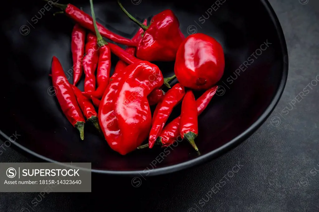 Black bowl of various red chili pods