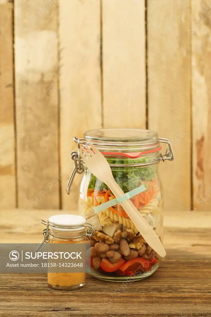 Preserving jar of vegan mixed salad with tofu and pasta and jar of cocktail sauce