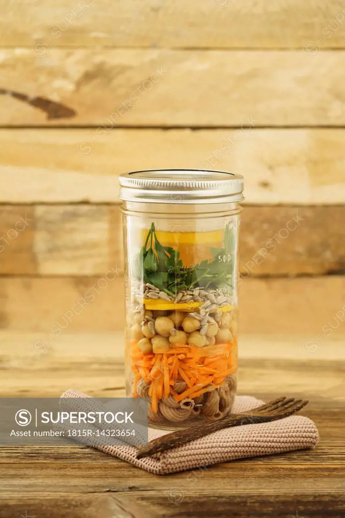 Glass of vegan mixed salad with whole-grain noodles, chick-peas and different vegetables