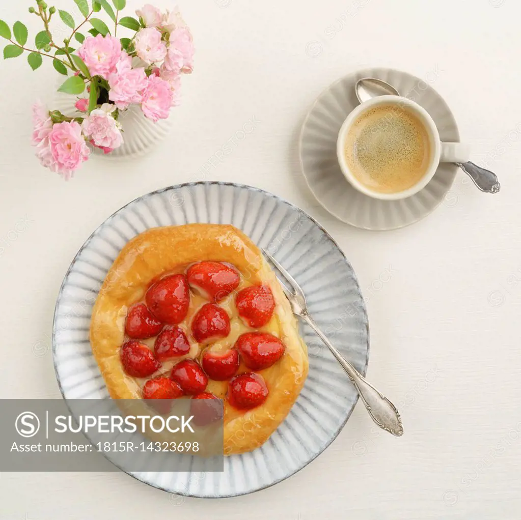 Flowers, coffee and Danish pastry with strawberries and custard