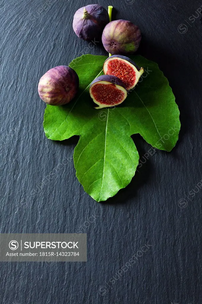 Sliced and whole figs and fig leaf on slate