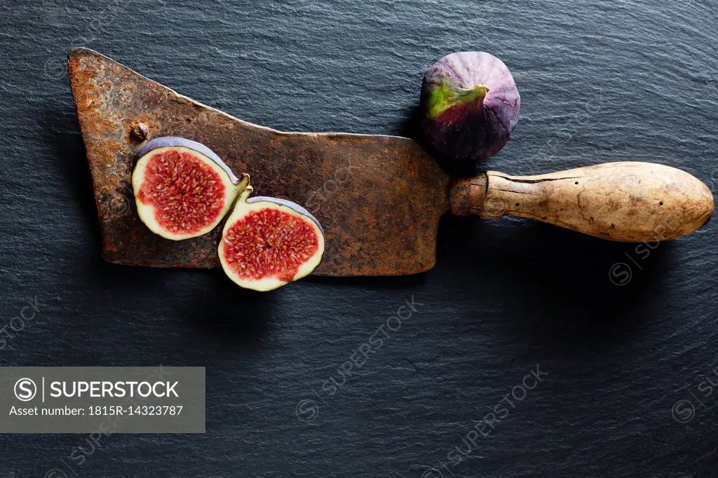 Sliced and whole fig and rusty cleaver on slate