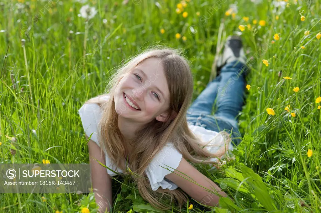 Germany, Bavaria, Portrait of girl lying on meadow, smiling