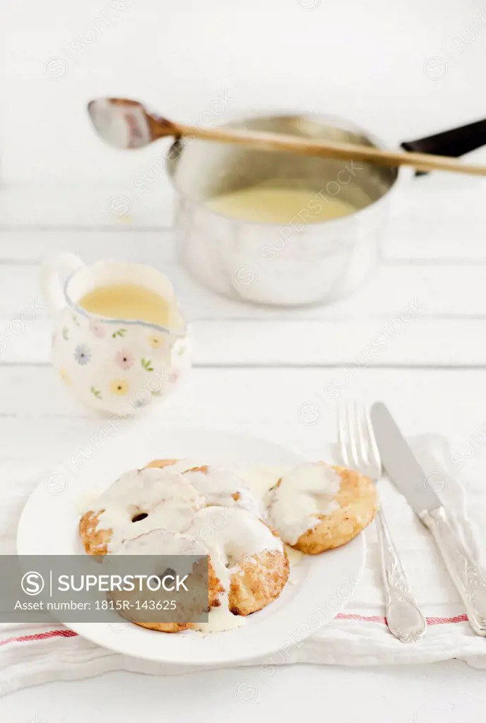 Apple fritters with custard on wooden table, close up