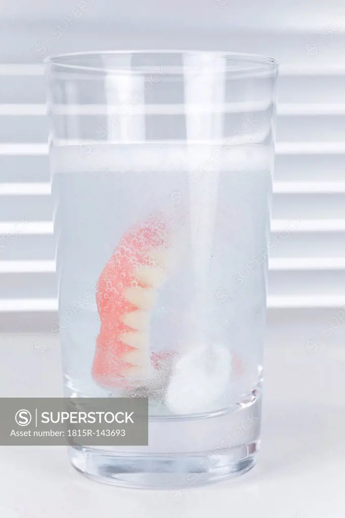Germany, Freiburg, Dental prothesis in glass of water with cleaning tablets