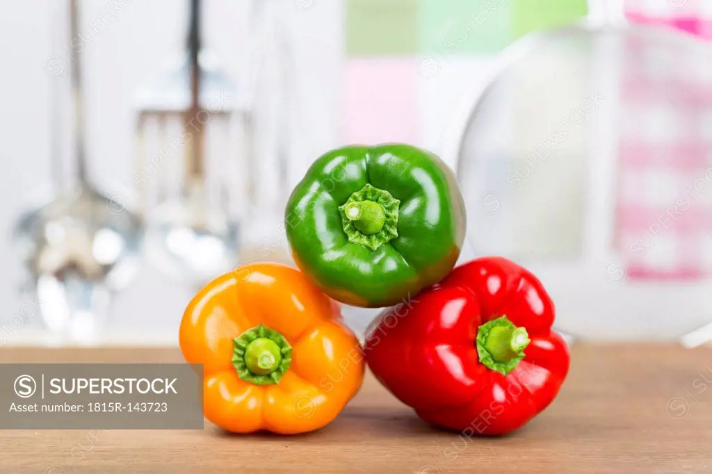 Germany, Freiburg, Red, Orange and green bell peppers on chopping board, close up