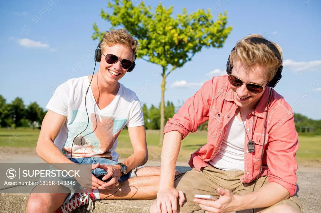 Germany, two young men wearing head phones, listening to music