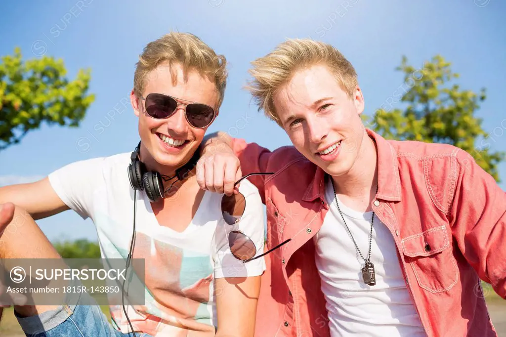 Germany, two friends listening to music with headphones