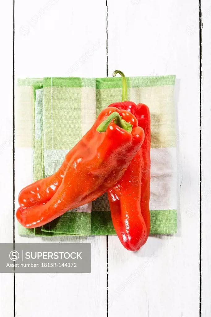 Red bell peppers with napkin on wooden table, close up