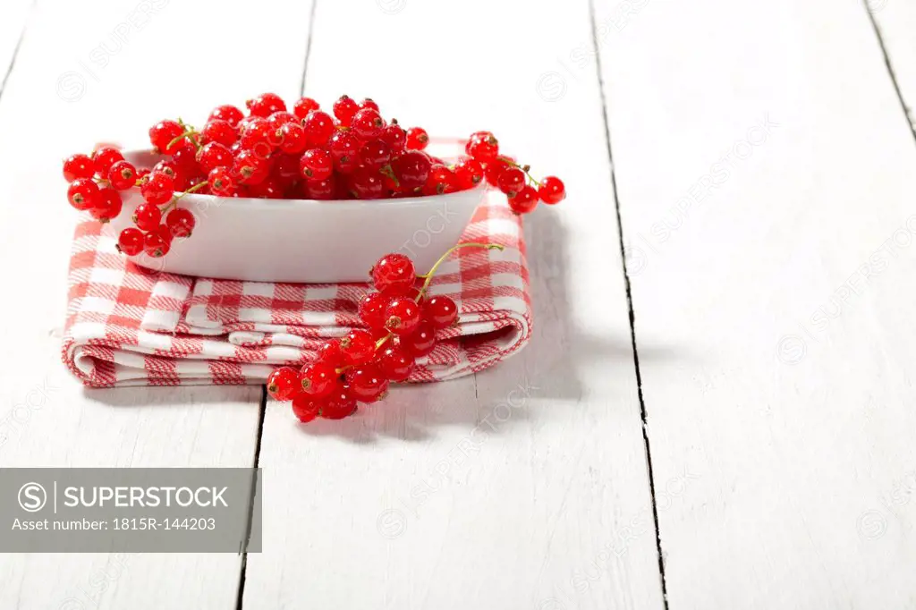 Bowl of currants on wooden table, close up