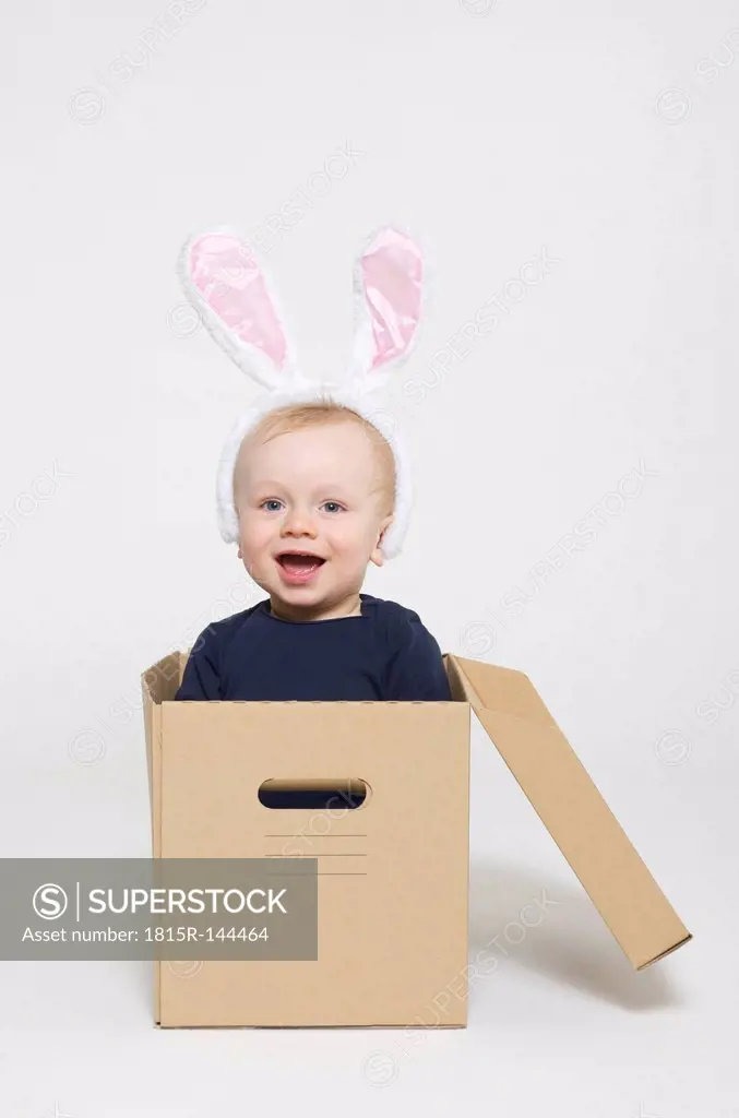 Portrait of baby boy wearing rabbit ears and sitting in box