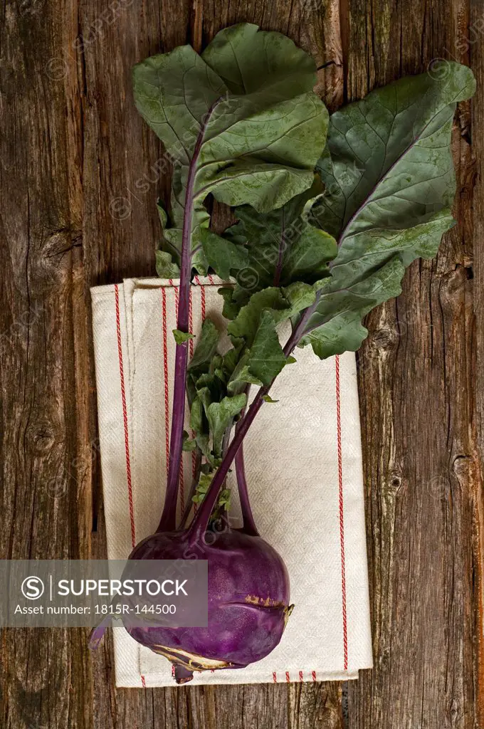 Blue cabbage turnip with napkin on wooden table, close up