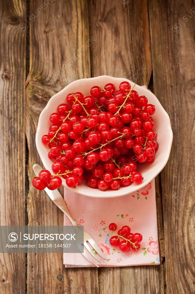 Bowl of red currants on napkin with fork, close up