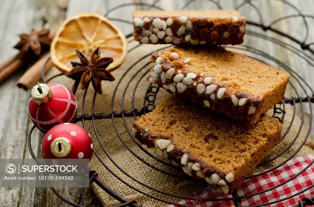 Gingerbread cake with christmas baubles and dried orange, spice on wooden table, close up