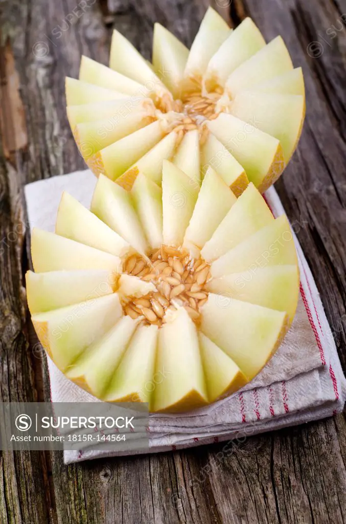 Honeydew melon with napkin on wooden table, close up