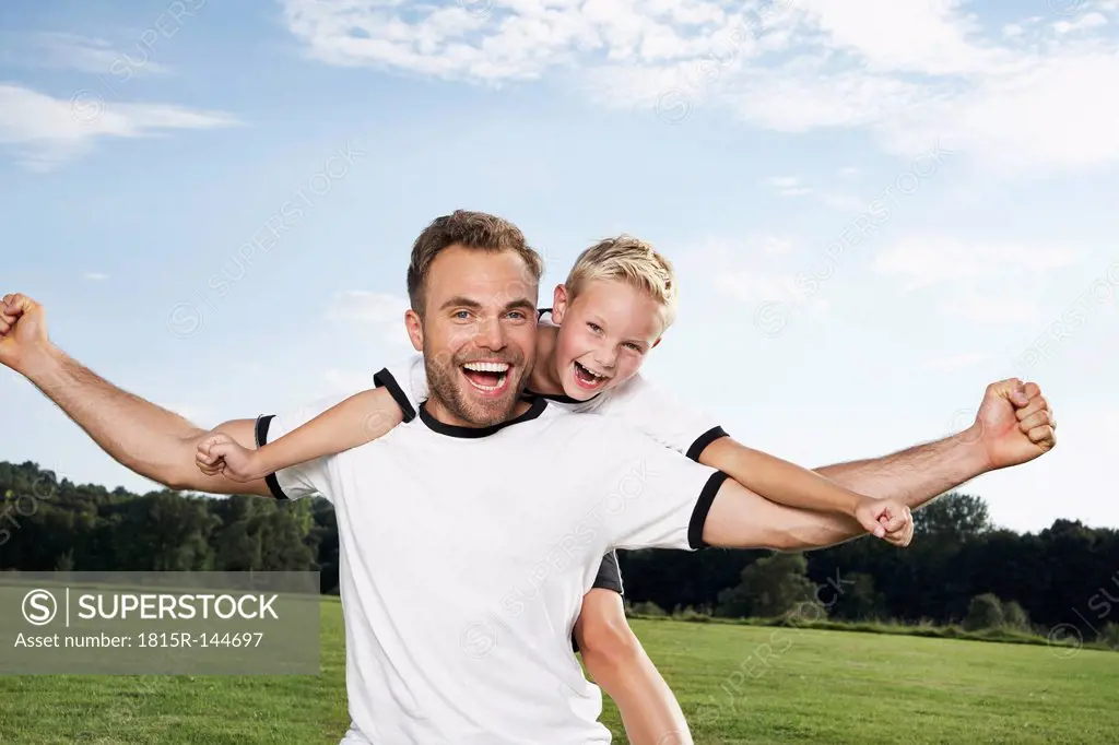 Germany, Cologne, Father and son cheering in football outfit