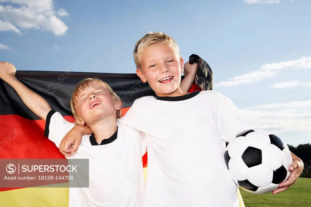 Germany, Cologne, Two boys wearing football shirts, holding German flag