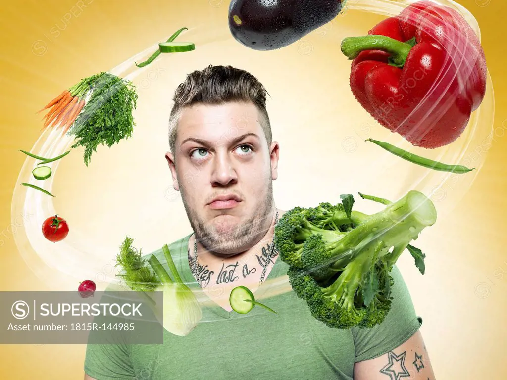 Young man looking at flying vegetables, Composite