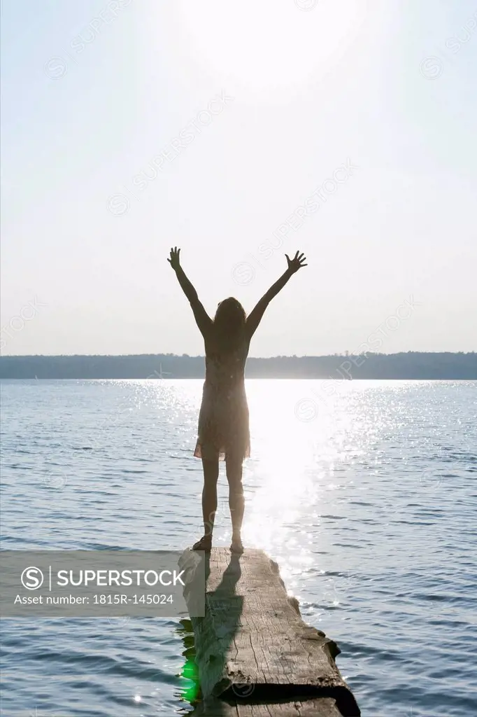 Germany, Bavaria, Mature woman standing with arms up at Lake Stamberg