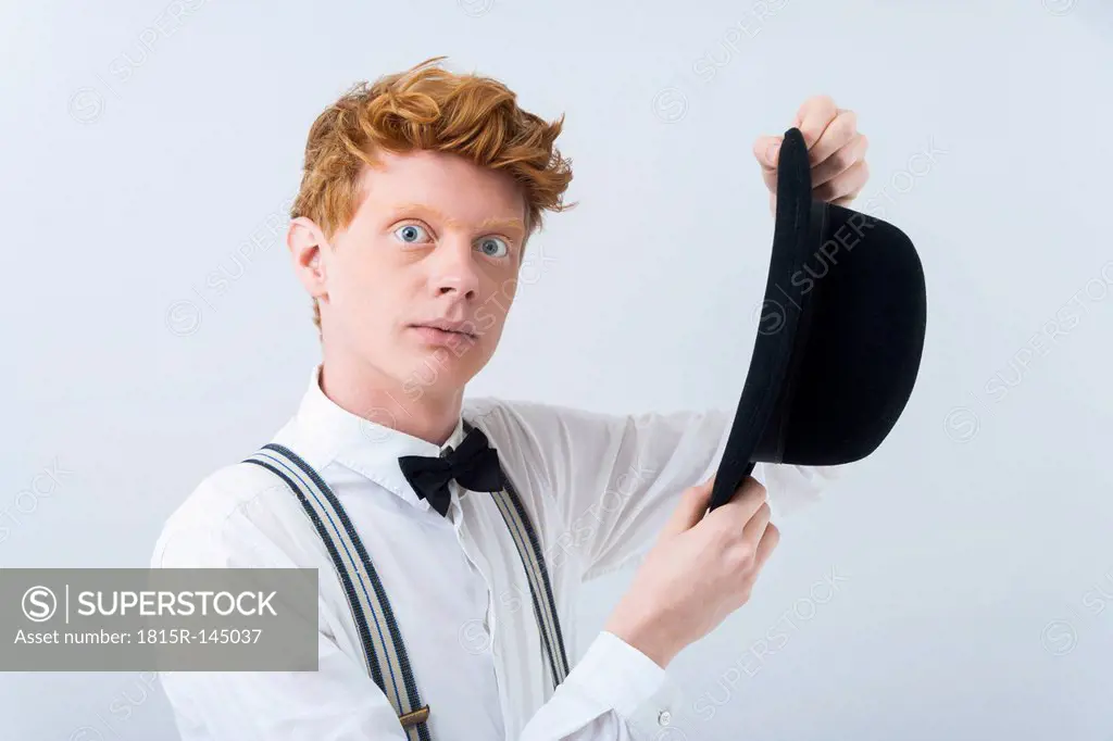 Portrait of young magician holding hat