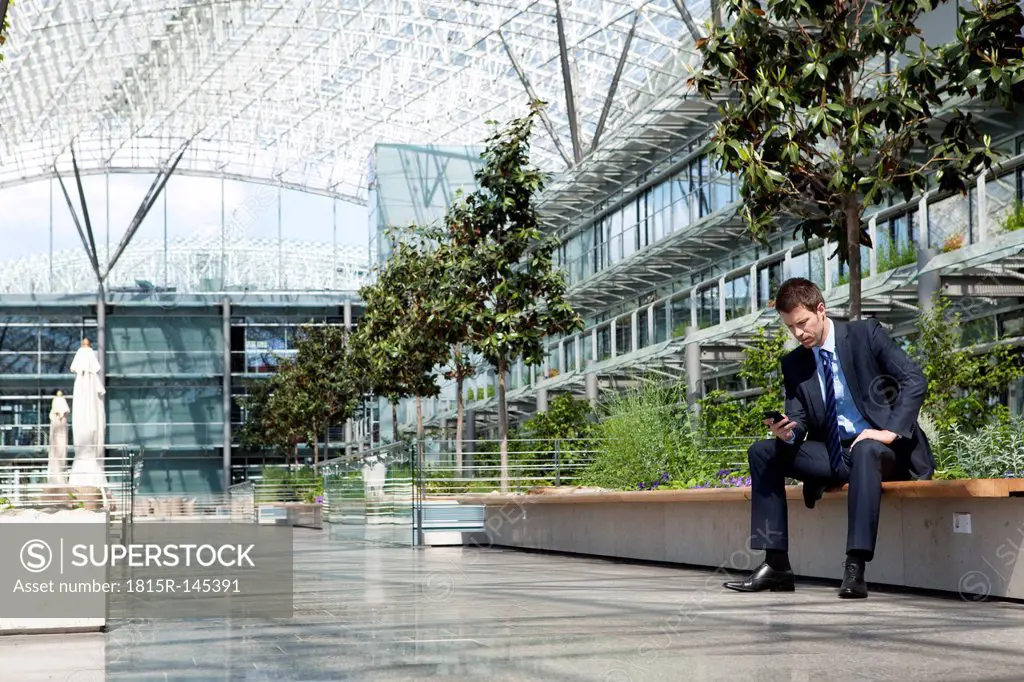 Businessman with cell phone in courtyard