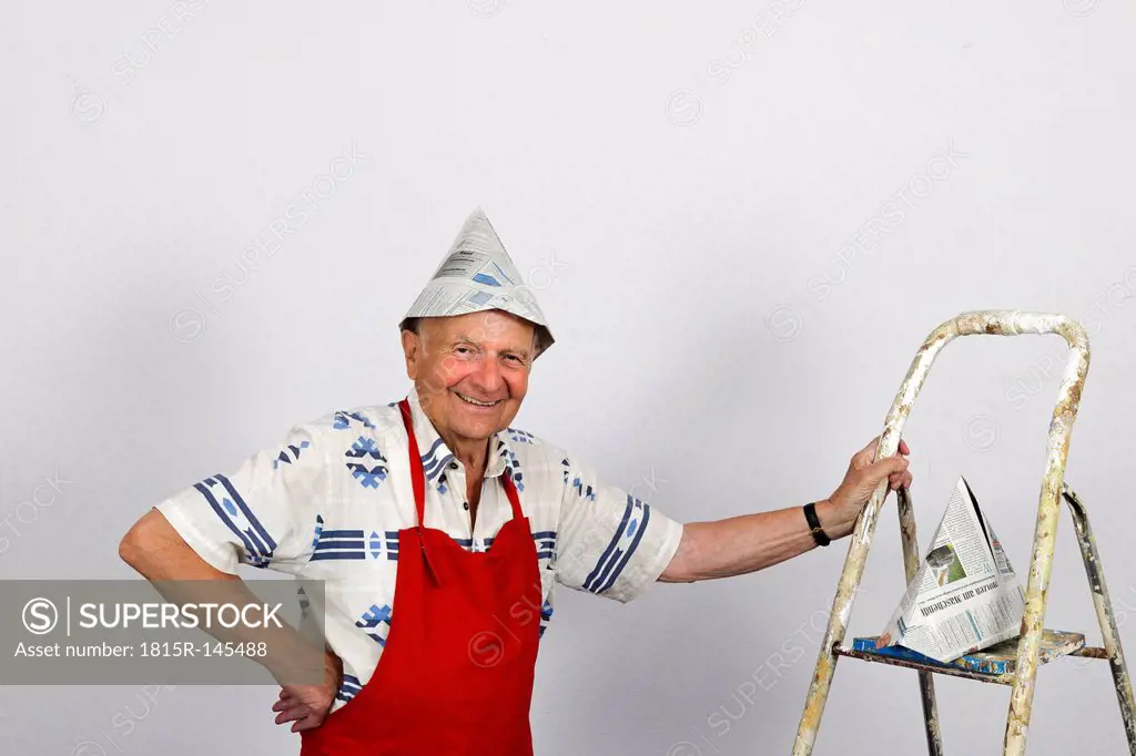 Germany, Portrait of senior man standing with holding step ladder, smiling