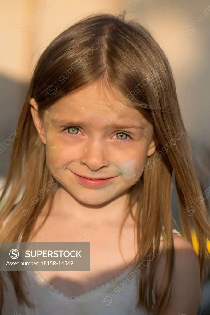 Portrait of smiling girl with coloured chalk in the face
