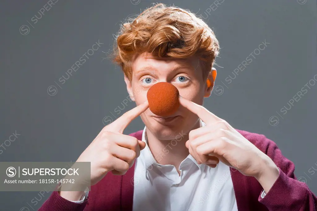 Portrait of young man holding ball on nose, close up