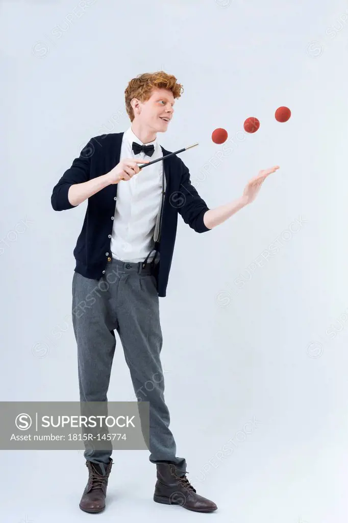 Young man showing magic with ball, smiling
