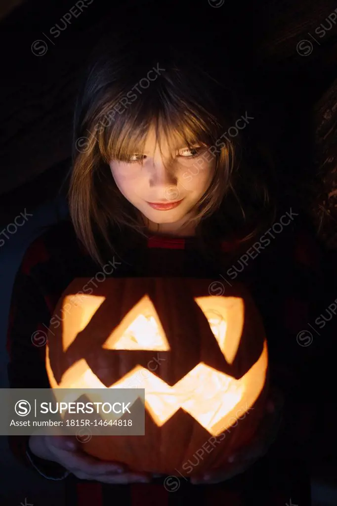 Portrait of girl with lighted Jack O'Lantern at Halloween
