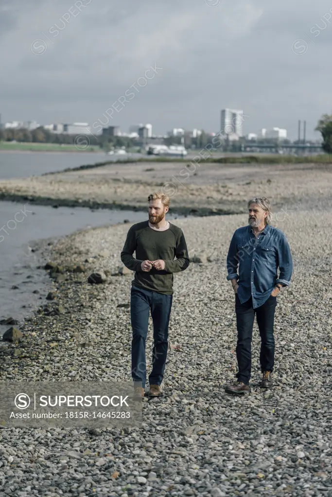 Father and son taking a stroll at Rhine river, meeting to talk