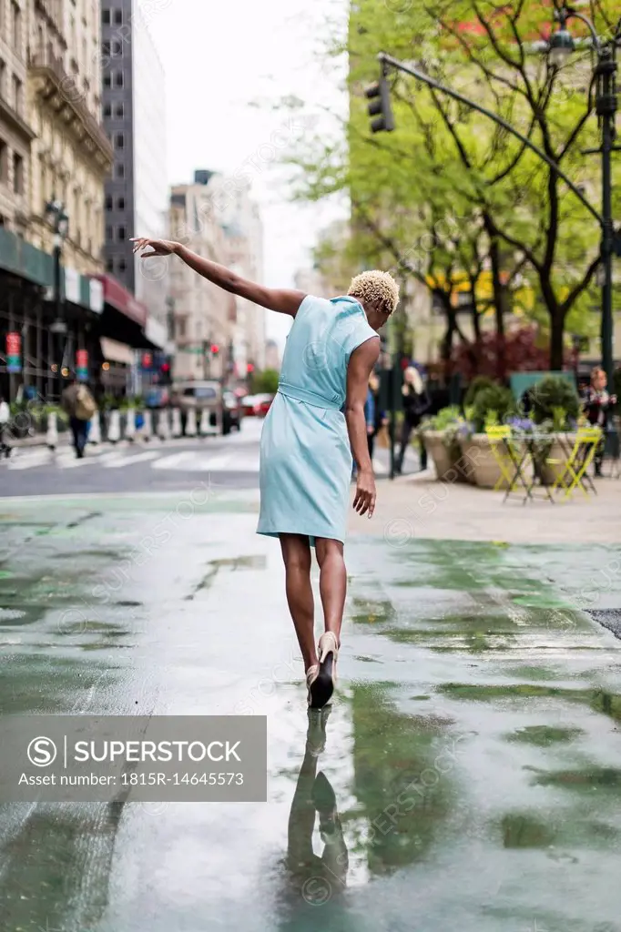 USA, New York, young blonde african-american woman walking in puddle