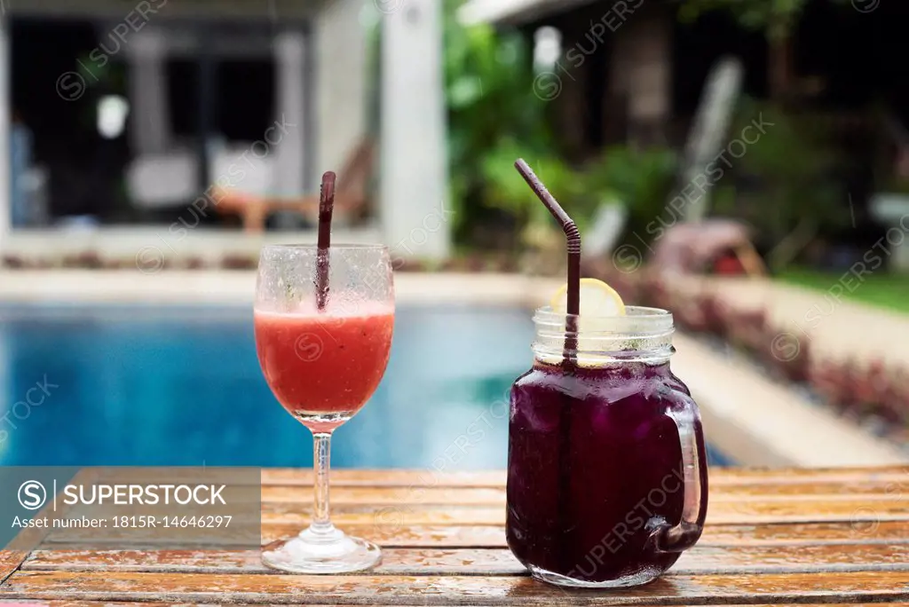 Two fruity cocktails at the poolside in rain